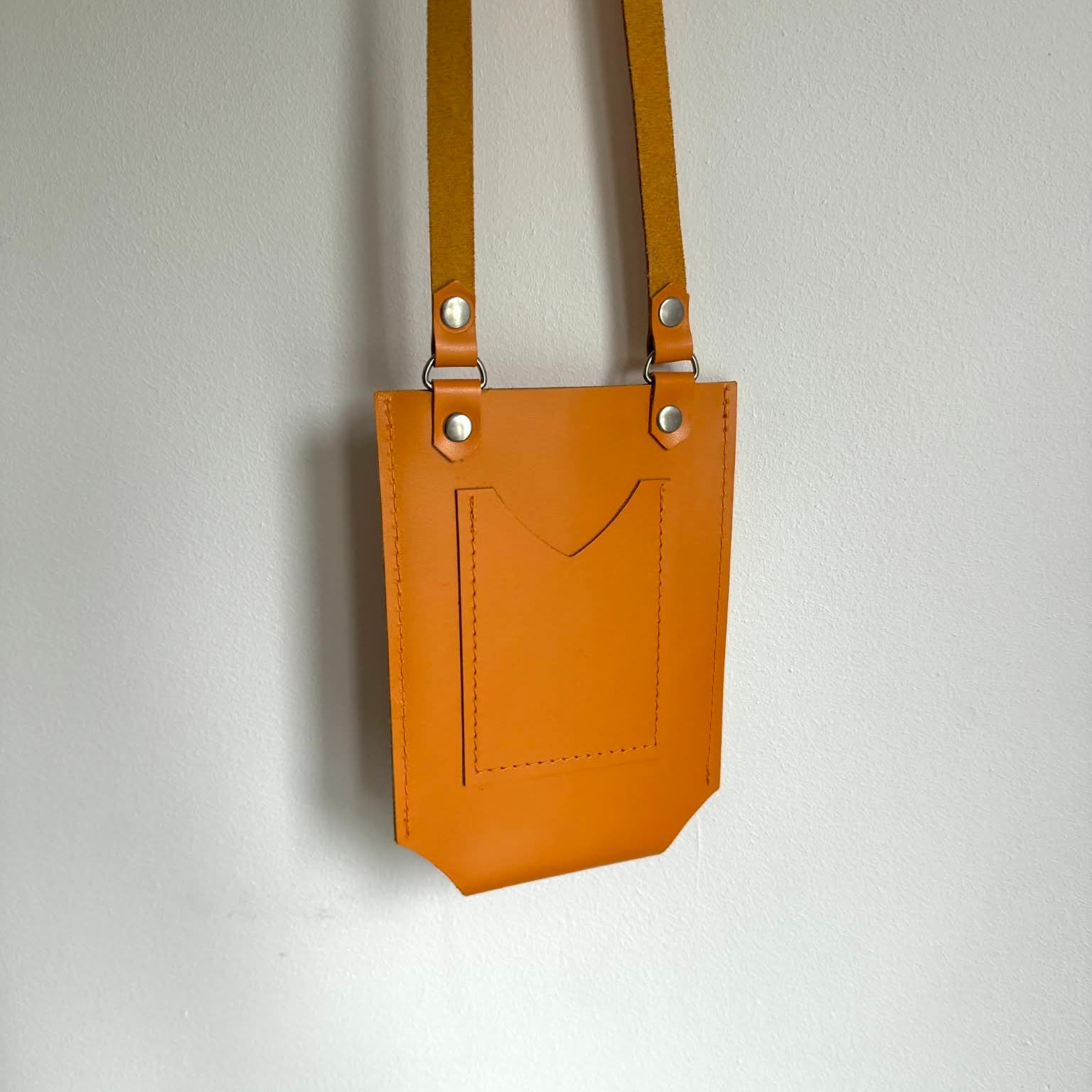 orange leather pouch with strap on a light gray background