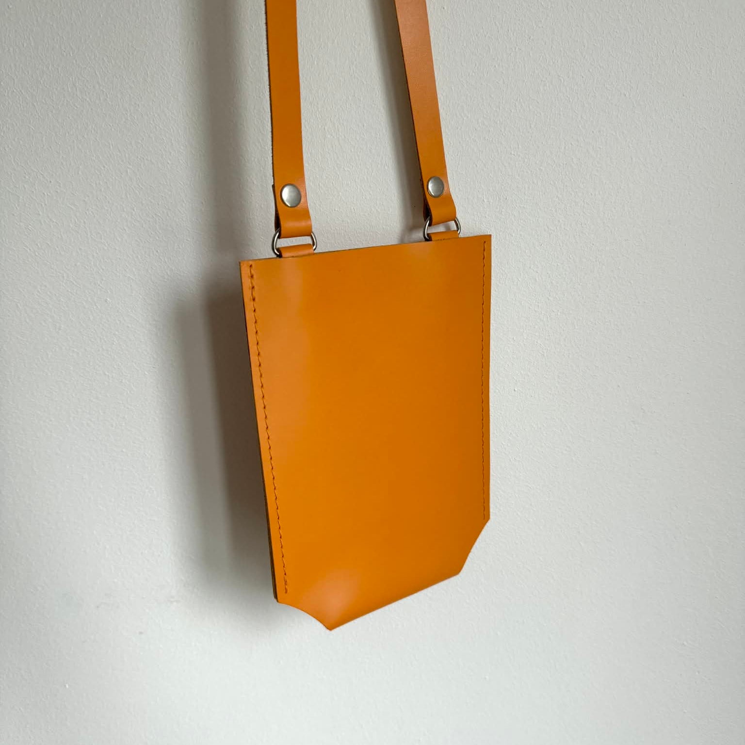 Orange leather crossbody bag on a light gray background