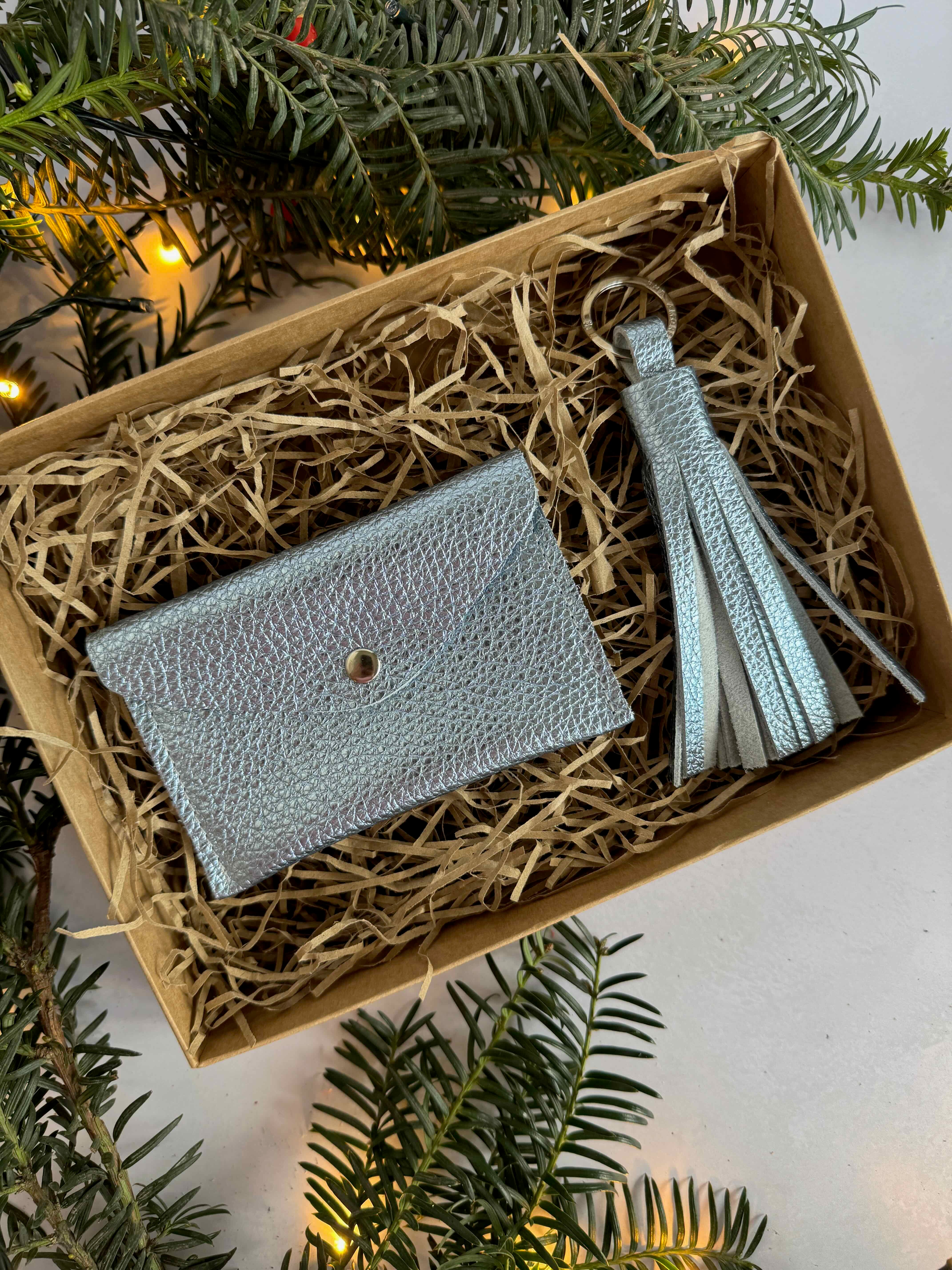 aquamarine leather wallet and tassel set in a box with greenery around