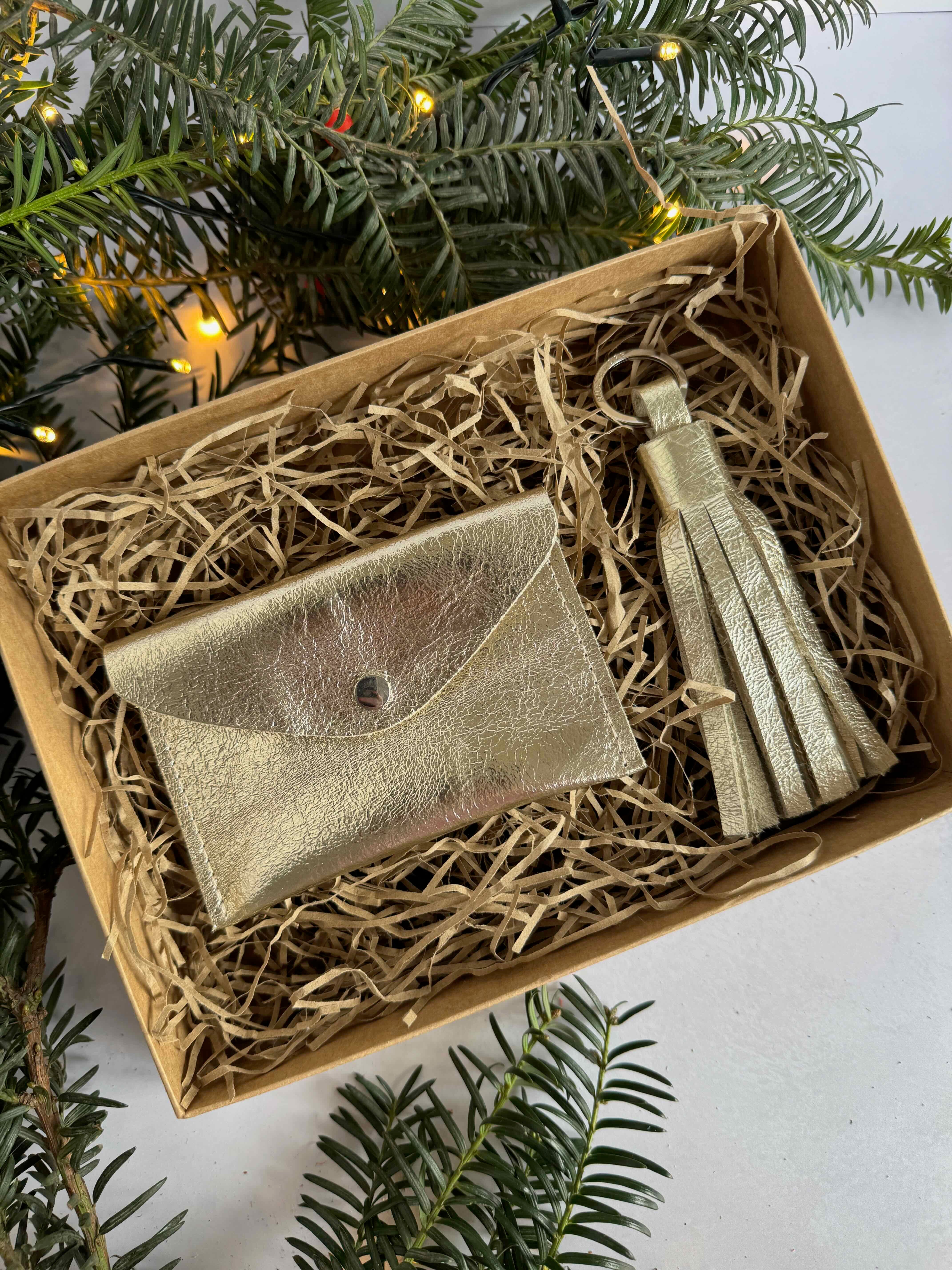 Gold purse and tassel in a decorative box with Christmas tree branches in the background