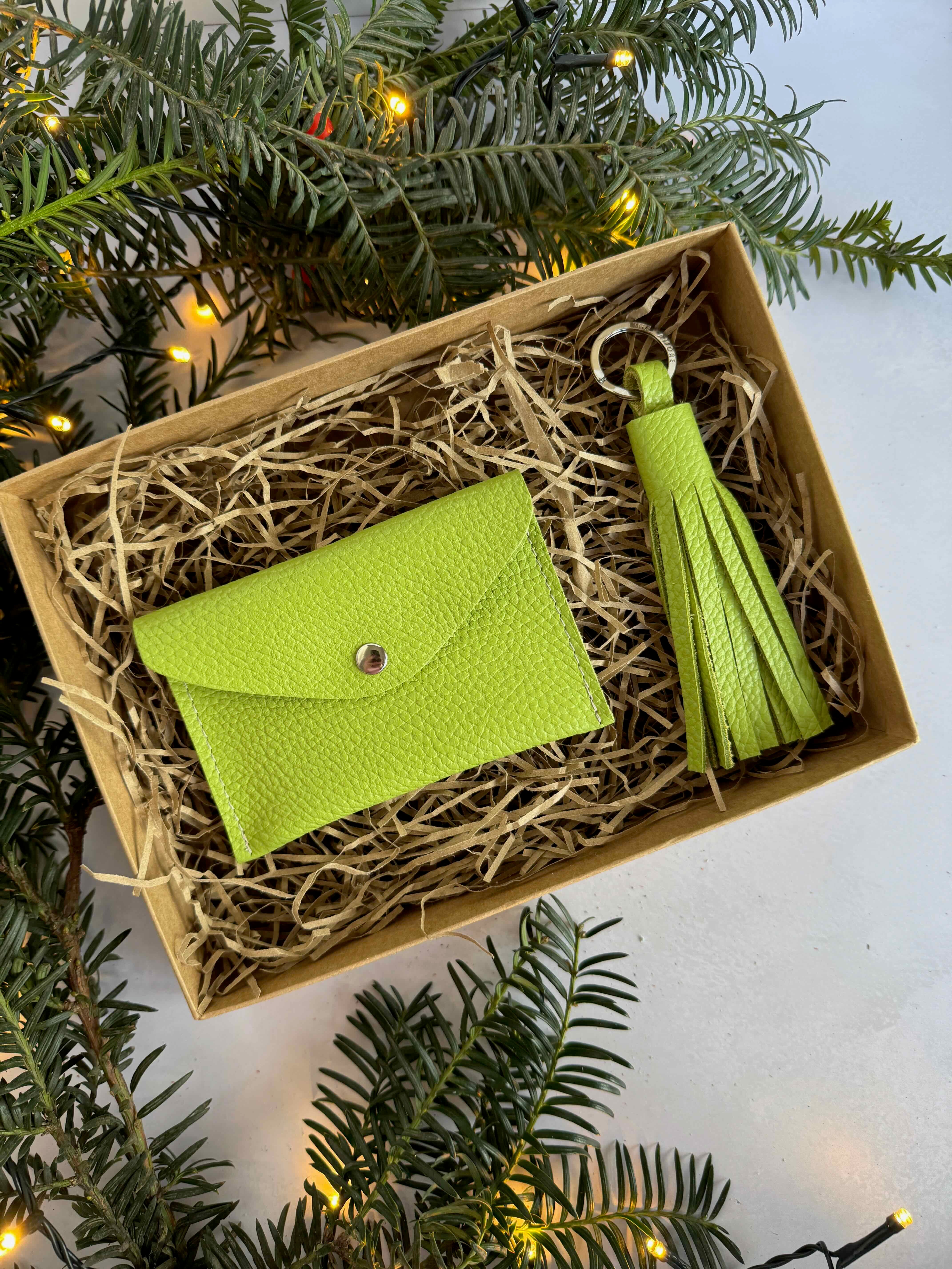 lime green leather wallet and tassel set in a box with Christmas tree branches in the background