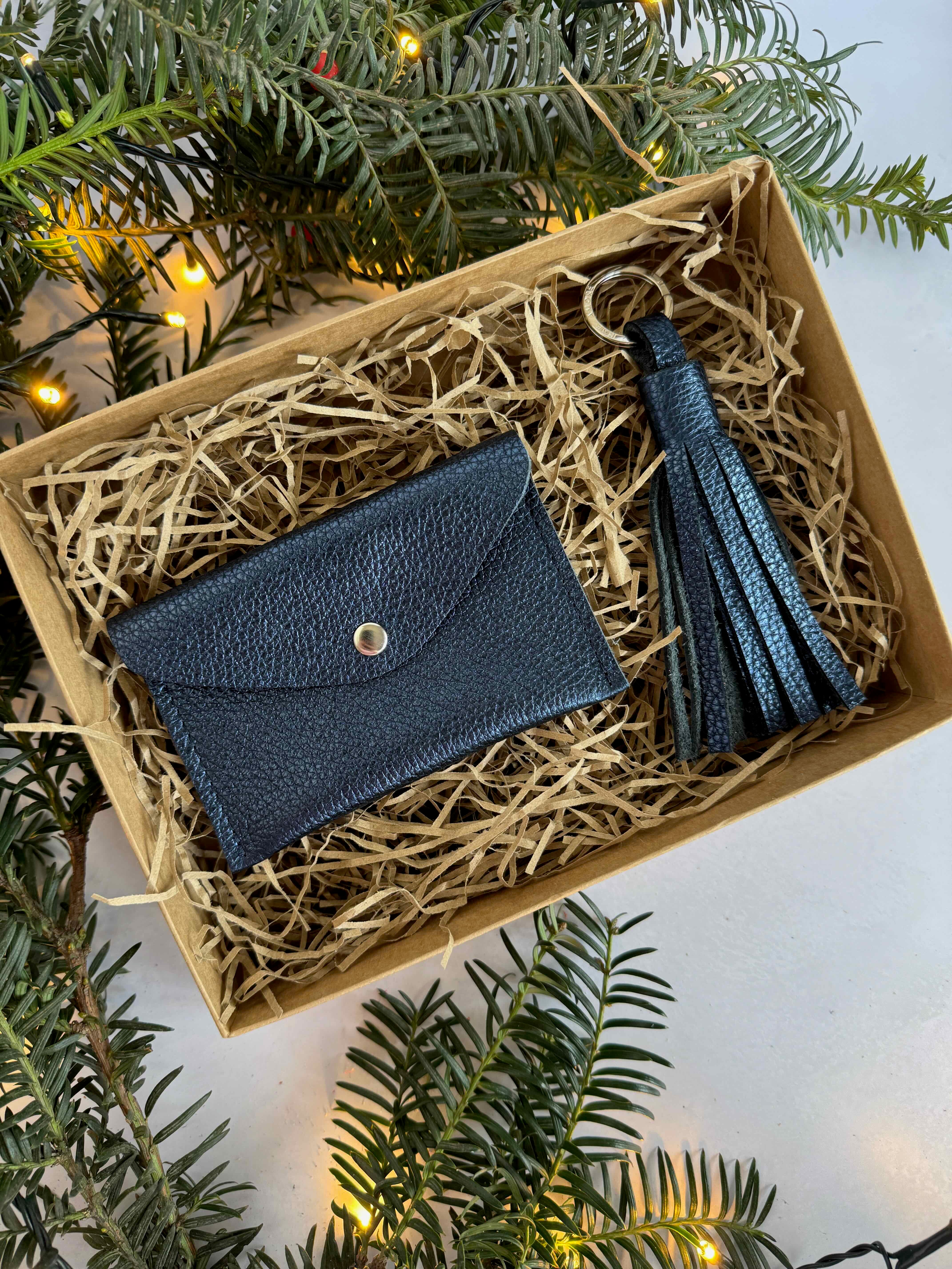 dark metallic leather wallet and tassel in a box with Christmas tree and lights in the background