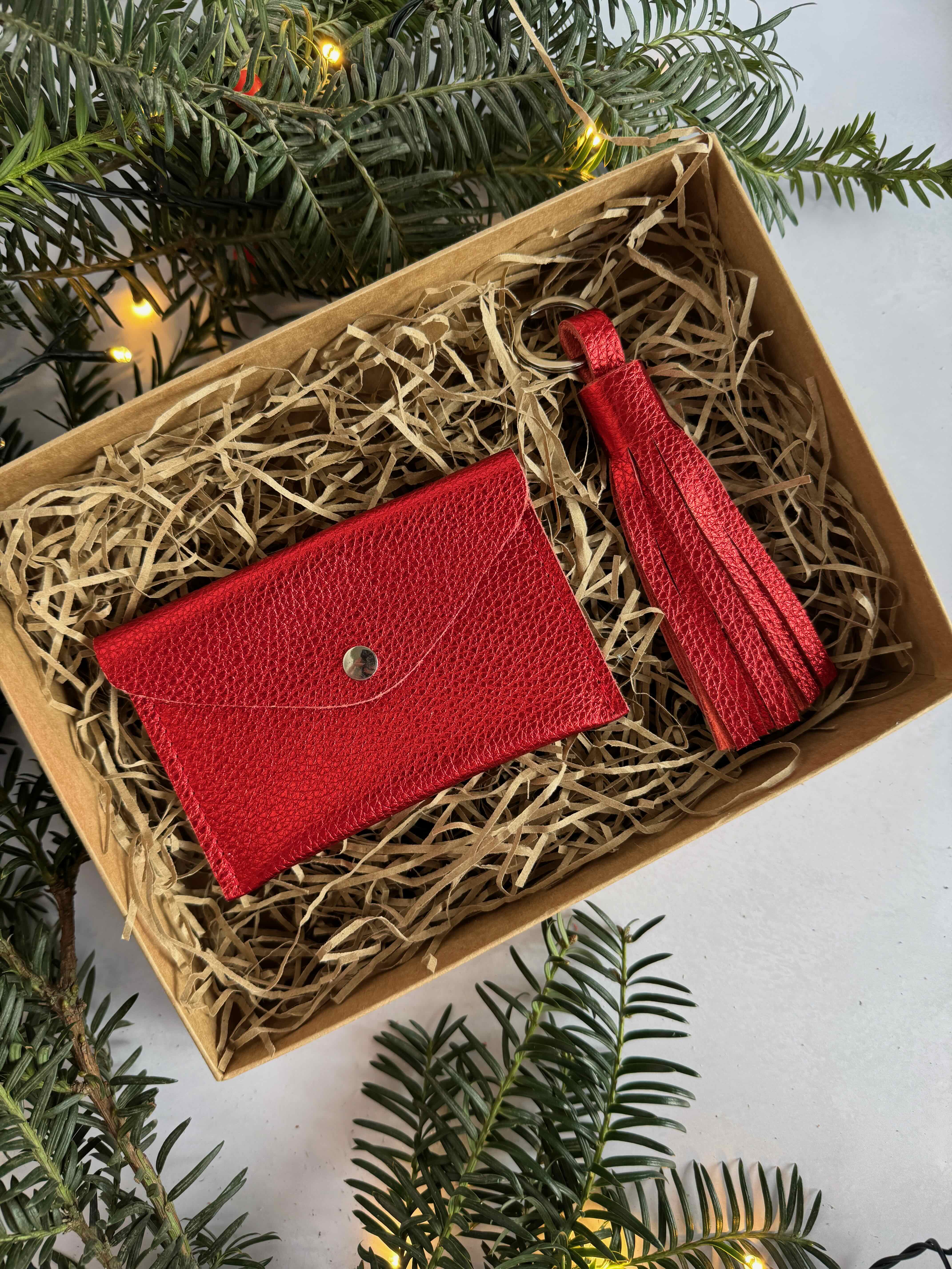 Red wallet and tassel set in a box with Christmas tree branches around